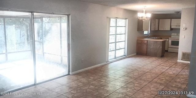 kitchen featuring an inviting chandelier, decorative light fixtures, white electric stove, and sink