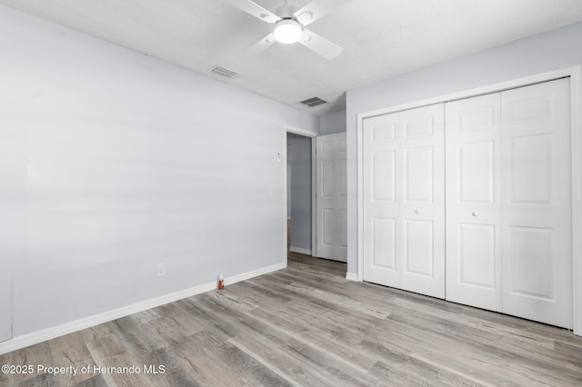 unfurnished bedroom with baseboards, wood finished floors, a closet, and visible vents