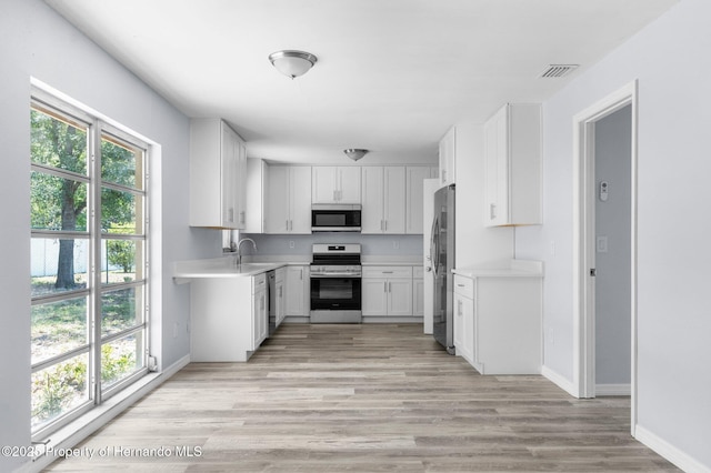 kitchen with light wood-style floors, visible vents, appliances with stainless steel finishes, a sink, and light countertops
