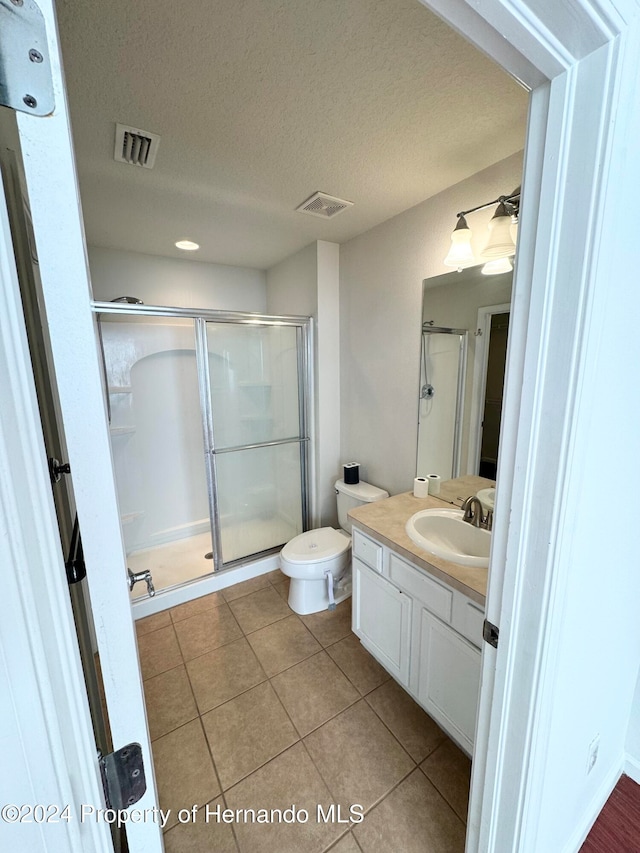 bathroom featuring tile patterned floors, vanity, an enclosed shower, and a textured ceiling