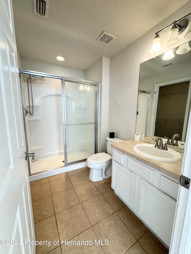 bathroom with tile patterned flooring, vanity, a textured ceiling, and a shower with shower door