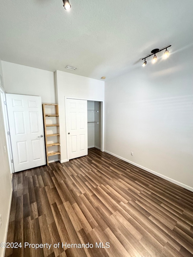 unfurnished bedroom featuring a closet, dark hardwood / wood-style flooring, and a textured ceiling