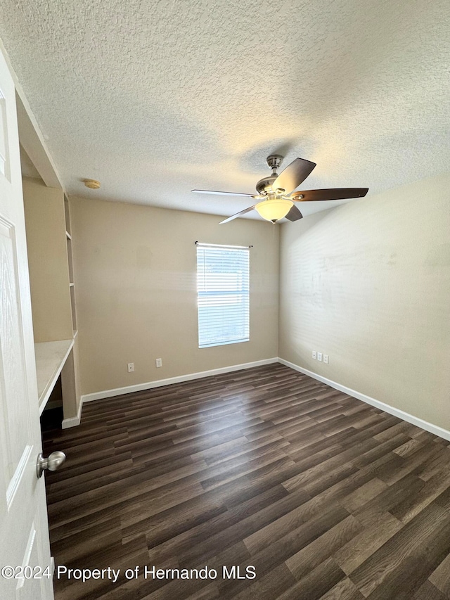 unfurnished room with a textured ceiling, ceiling fan, and dark hardwood / wood-style floors