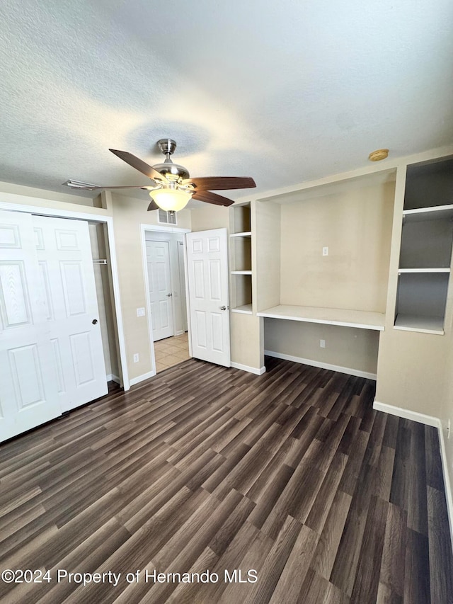 unfurnished bedroom featuring a closet, ceiling fan, dark hardwood / wood-style flooring, and a textured ceiling