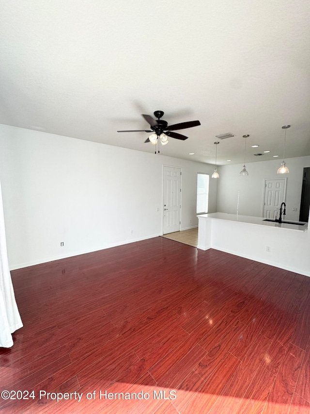 unfurnished living room featuring ceiling fan, sink, and dark hardwood / wood-style floors