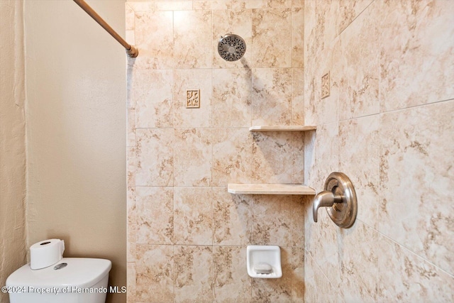 bathroom featuring tiled shower and toilet