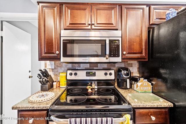 kitchen with light stone countertops, backsplash, and stainless steel appliances