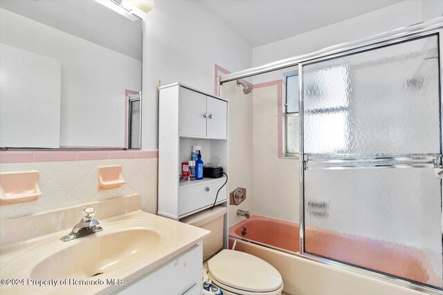 full bathroom featuring decorative backsplash, toilet, vanity, and combined bath / shower with glass door