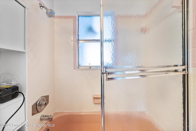 bathroom with toilet and bath / shower combo with glass door