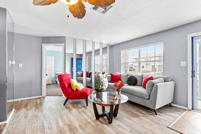 living room with ceiling fan, light hardwood / wood-style floors, and a textured ceiling