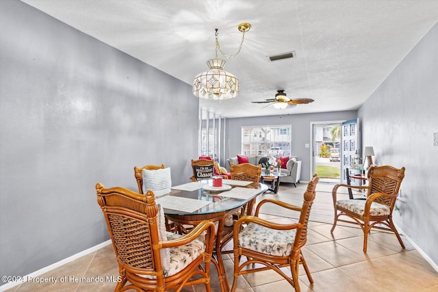 tiled dining space with ceiling fan with notable chandelier and a textured ceiling