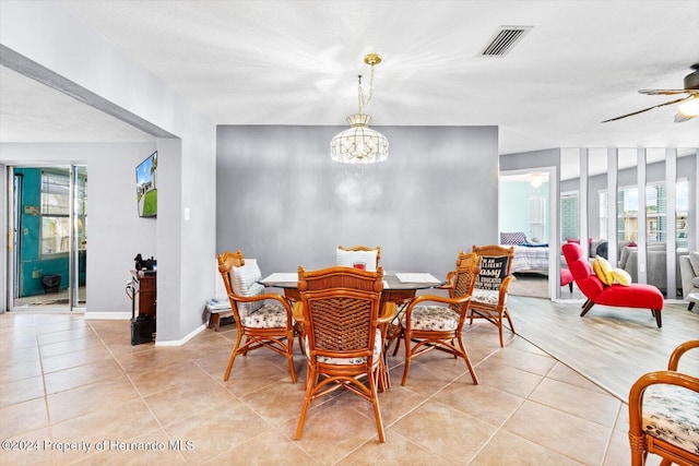 tiled dining space featuring a healthy amount of sunlight and ceiling fan with notable chandelier