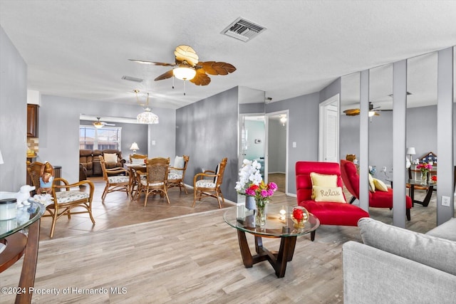 living room with ceiling fan, light hardwood / wood-style floors, and a textured ceiling