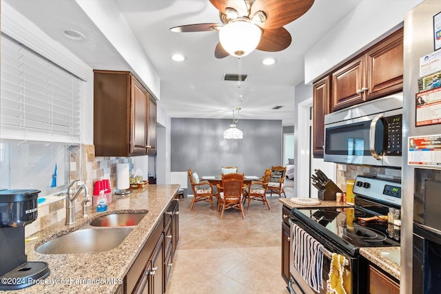 kitchen with sink, appliances with stainless steel finishes, tasteful backsplash, decorative light fixtures, and light stone counters