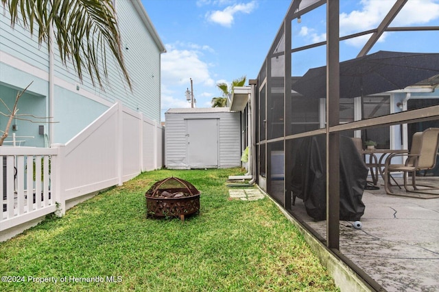 view of yard with a fire pit, a patio area, a lanai, and a storage shed