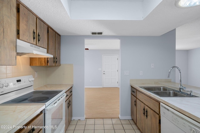 kitchen with decorative backsplash, a textured ceiling, white appliances, sink, and light tile patterned flooring