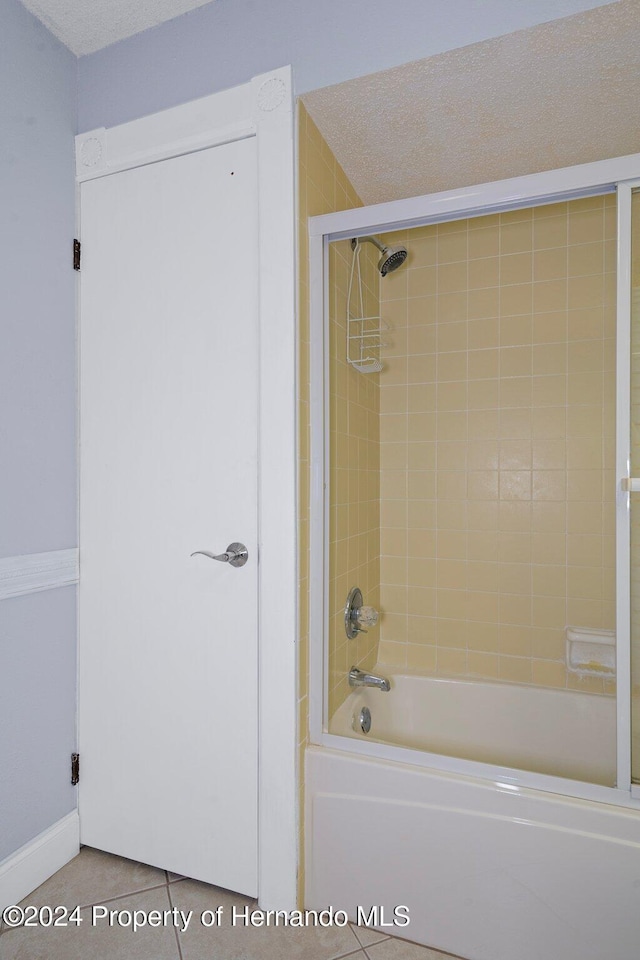 bathroom with tile patterned floors, a textured ceiling, and tiled shower / bath combo