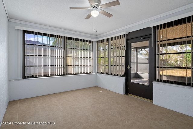 interior space with a textured ceiling, tile patterned floors, ceiling fan, and ornamental molding