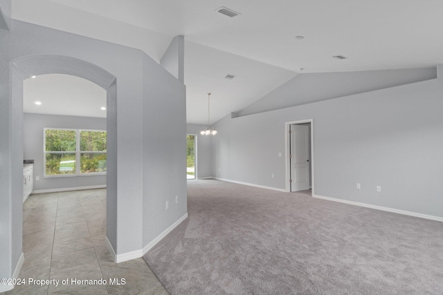 empty room with light colored carpet, vaulted ceiling, and an inviting chandelier