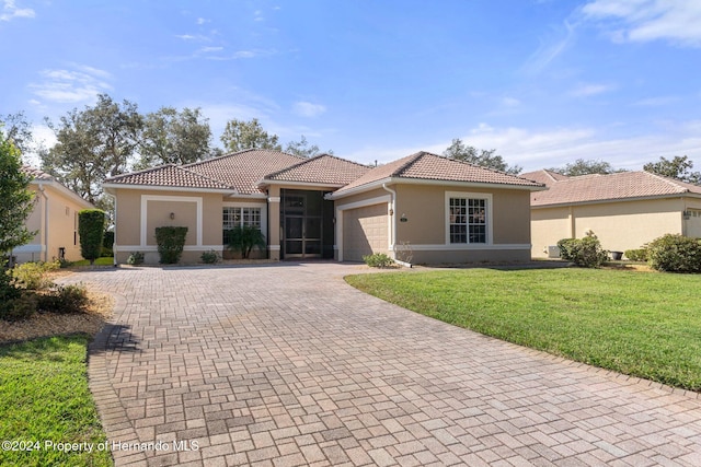 mediterranean / spanish-style house featuring a front yard and a garage