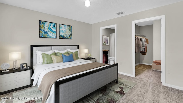 carpeted bedroom featuring connected bathroom, a spacious closet, and a closet