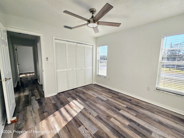 unfurnished bedroom with a textured ceiling, dark hardwood / wood-style floors, a closet, and ceiling fan