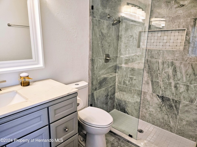 bathroom with tiled shower, vanity, and toilet