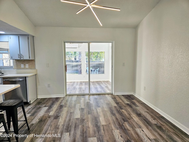 unfurnished dining area with a wealth of natural light, dark hardwood / wood-style flooring, and a notable chandelier