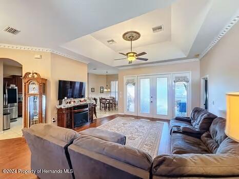 living room featuring a raised ceiling, ceiling fan, and light hardwood / wood-style floors