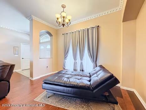 bedroom with a notable chandelier, dark hardwood / wood-style flooring, and ornamental molding