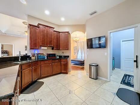 kitchen with sink, light tile patterned floors, and ceiling fan with notable chandelier