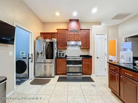 kitchen with washer / dryer, stainless steel appliances, and light tile patterned flooring