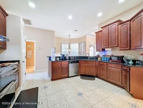 kitchen featuring kitchen peninsula, decorative light fixtures, stainless steel appliances, and sink