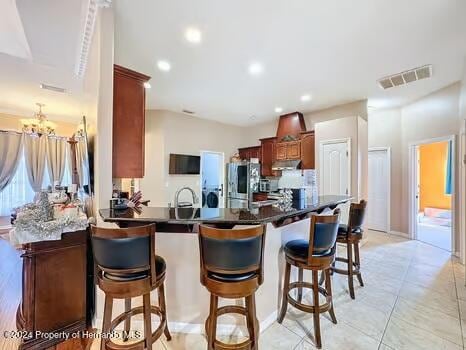 kitchen with kitchen peninsula, stainless steel fridge, a kitchen breakfast bar, and a notable chandelier