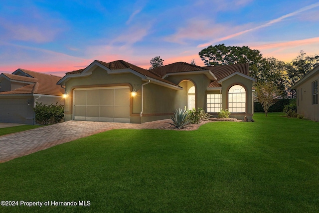 mediterranean / spanish home with a garage and a lawn