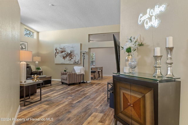 living room with hardwood / wood-style flooring, a textured ceiling, and vaulted ceiling