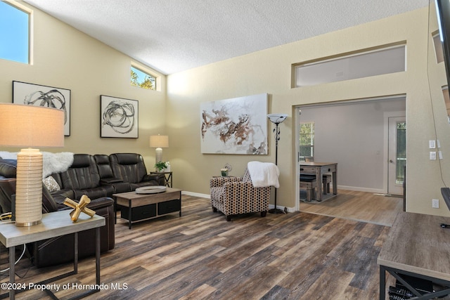 living room featuring a textured ceiling, a wealth of natural light, and dark wood-type flooring