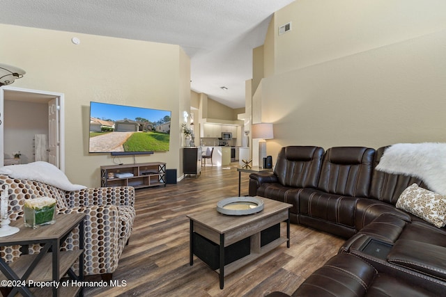 living room featuring dark hardwood / wood-style flooring, a textured ceiling, and high vaulted ceiling