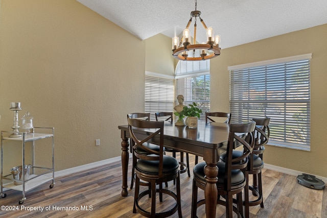 dining room featuring wood-type flooring, a textured ceiling, an inviting chandelier, and lofted ceiling