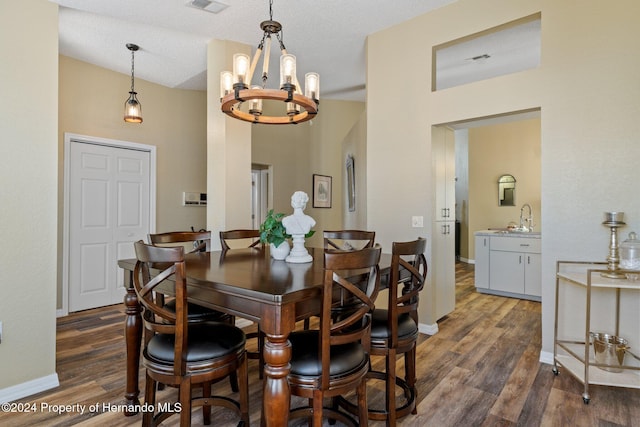 dining room featuring a textured ceiling, sink, dark wood-type flooring, and a chandelier