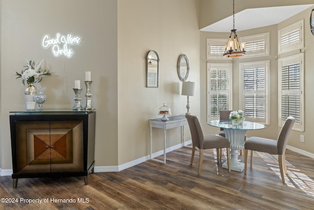 dining room with dark hardwood / wood-style flooring, a high ceiling, and an inviting chandelier