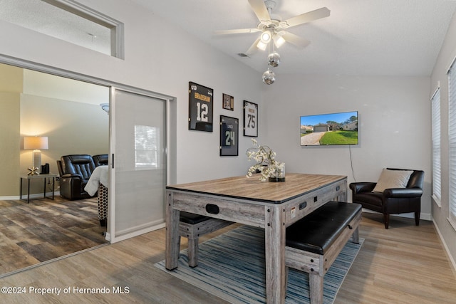 dining space with a healthy amount of sunlight, ceiling fan, wood-type flooring, and vaulted ceiling