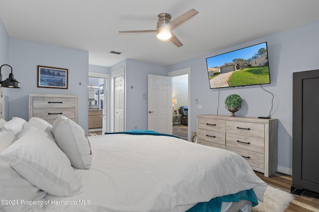 bedroom featuring dark hardwood / wood-style floors, ensuite bath, and ceiling fan