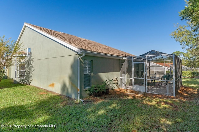 view of property exterior with a lawn and glass enclosure