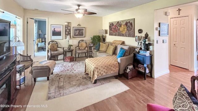 living room with hardwood / wood-style flooring, a textured ceiling, and ceiling fan