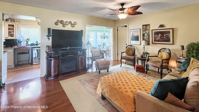 living room featuring ceiling fan, a fireplace, dark hardwood / wood-style flooring, and a textured ceiling