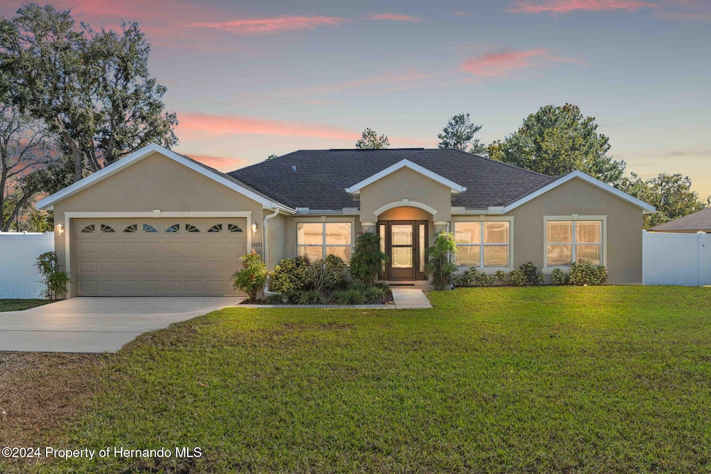 ranch-style home with a garage and a yard