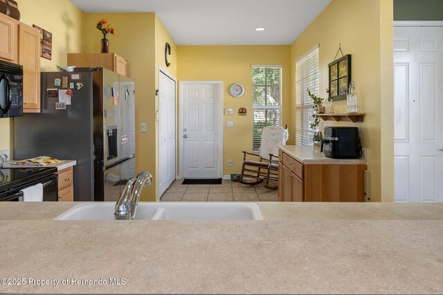 kitchen featuring light tile patterned floors, sink, and black appliances