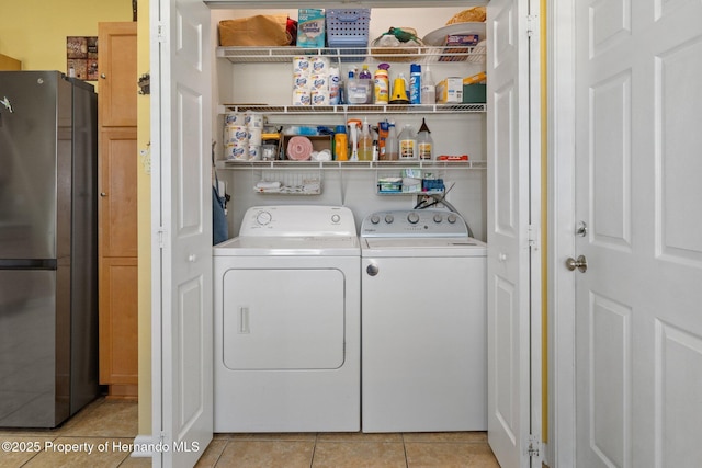 clothes washing area featuring light tile patterned flooring and washer and clothes dryer