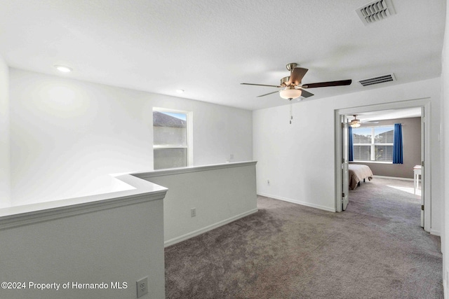 carpeted spare room with ceiling fan and a textured ceiling